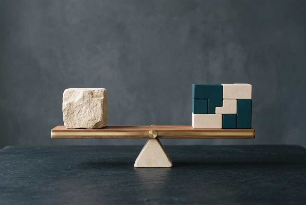 Balanced timber beam on a stone fulcrum comparing a single stone block against seven interlocking teal and ivory blocks